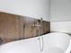 Modern bathroom featuring a sleek white tub and stylish wood-look tile accent wall at 2531 Sw 167Th Loop, Ocala, FL 34473