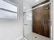 Modern shower with wood look tile accents, glass doors, and white tile flooring at 2531 Sw 167Th Loop, Ocala, FL 34473