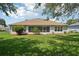 Well-maintained backyard featuring a large lawn and landscaping along the back of the house and a view of the screened lanai at 26609 Bull Run, Leesburg, FL 34748
