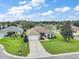 Aerial view of a home with a well-manicured lawn, driveway, and landscaping with mature trees and green shrubs at 26609 Bull Run, Leesburg, FL 34748