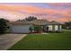 Charming single-story home featuring a well-manicured lawn and inviting curb appeal against a colorful sunset sky at 26609 Bull Run, Leesburg, FL 34748