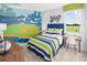 Vibrant bedroom with fun stadium mural, striped bedding, and bright green accents at 2681 Ginseng Ivy St, Apopka, FL 32703