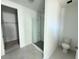 Modern bathroom with walk-in glass shower and toilet, next to a walk-in closet with white walls and gray tile flooring at 30112 Misty Pines Rd, Mount Dora, FL 32757