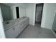 New bathroom featuring double vanity, quartz countertop, gray cabinets, tile floor, walk-in closet and large mirror at 30112 Misty Pines Rd, Mount Dora, FL 32757