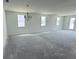 Bright, open living room with multiple windows, a modern chandelier, and access to an outdoor space at 30112 Misty Pines Rd, Mount Dora, FL 32757
