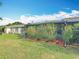 Well-maintained backyard featuring lush green grass, vibrant hibiscus bushes, and a screened-in porch at 3208 W Tower Ct, Kissimmee, FL 34741