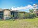 Backyard featuring lush green grass, vibrant hibiscus bushes, screened-in porch, and a satellite dish at 3208 W Tower Ct, Kissimmee, FL 34741