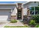 An inviting front entrance with stone accents, a stained wood door, and lush landscaping at 405 E Freesia Ct, Deland, FL 32724
