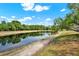 Scenic view of the pond behind the property with lush greenery, a walking path, and blue skies with white clouds at 4406 Brookstone Ct, Orlando, FL 32826