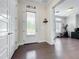 Hallway featuring hardwood floors, white trim, and a glimpse into a bright room with large windows at 473 Oviedo Blvd, Oviedo, FL 32765