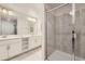 Well-lit bathroom featuring double sinks, white cabinets, and a tiled walk-in shower at 4731 Clock Tower Dr # 105, Kissimmee, FL 34746