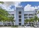 Exterior of a modern condo building with palm trees and well-manicured landscaping on a partly cloudy day at 4731 Clock Tower Dr # 105, Kissimmee, FL 34746