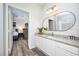 Well-lit bathroom featuring granite countertop, sleek white cabinets, and a modern mirror with an adjacent bedroom at 4802 Cayview Ave # 301, Orlando, FL 32819