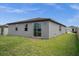 Home backyard featuring a well-maintained lawn and gray exterior walls with a sliding glass door at 523 Tortugas St, Haines City, FL 33844
