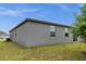 Spacious backyard featuring lush grass and gray exterior walls with bright window accents at 523 Tortugas St, Haines City, FL 33844