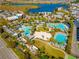 Aerial view showcasing community pools, sports courts, and amenities with a lake backdrop at 7789 Nemours Pkwy, Orlando, FL 32827