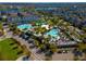 Aerial view of community pools, clubhouse, and surrounding neighborhood with lake in background at 7789 Nemours Pkwy, Orlando, FL 32827