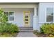 A welcoming, light-filled entrance with a bright yellow front door with modern glass panels and a brick walkway at 7789 Nemours Pkwy, Orlando, FL 32827