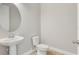 Clean half bathroom with a pedestal sink, toilet, and round mirror at 7789 Nemours Pkwy, Orlando, FL 32827
