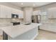 Modern kitchen featuring a spacious island with stainless steel appliances and white cabinets at 7789 Nemours Pkwy, Orlando, FL 32827