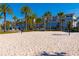 A well-maintained beach volleyball court with clear blue skies, palm trees, and nearby seating at 7789 Nemours Pkwy, Orlando, FL 32827