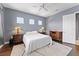 Bedroom featuring hardwood floors, a ceiling fan, and three windows for natural light at 8436 Tavistock Lakes Boulevard, Orlando, FL 32827