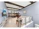 Open-concept living room with wood beam ceilings, a modern glass railing, and views of the kitchen and dining area at 8436 Tavistock Lakes Boulevard, Orlando, FL 32827