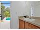 Half bathroom with a vanity, sink, and a view of the screened patio and swimming pool at 941 Clear Creek Cir, Clermont, FL 34714