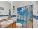 Bright bathroom with a sink, toilet, framed mirror, and a shower curtain with beach scenery at 9836 Lake District Ln, Orlando, FL 32832