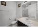 Clean and bright bathroom featuring a white vanity and toilet, complemented by a framed mirror and glass-enclosed shower at 1165 Stratton Ave, Groveland, FL 34736