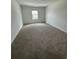 Bright bedroom features neutral carpet, a window letting in natural light, and white walls at 1190 Seaside Mist Trl, Kissimmee, FL 34747