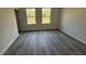A cozy bedroom featuring two large windows providing natural light and wood-look vinyl floors at 13265 Sw 85Th Cir, Ocala, FL 34473