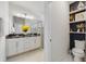 Well-lit bathroom featuring double sinks, a dark marble countertop, white cabinetry and stylish decorations on shelves at 1396 Riley Cir, Deland, FL 32724
