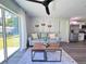 Bright living room with a gray sofa, rustic coffee table, and a large sliding glass door at 14 Fir Trail Way, Ocala, FL 34472