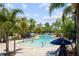 Community pool featuring zero entry with fountains and splash features, surrounded by lounge chairs, umbrellas, and palm trees at 14501 Grove Resort Ave # 3636, Winter Garden, FL 34787