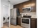 Modern kitchen featuring stainless steel appliances and an open doorway to a laundry area with stacked machines at 14501 Grove Resort Ave # 3636, Winter Garden, FL 34787