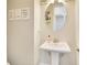 Neat half bathroom featuring a pedestal sink, an oval mirror, and decorative artwork at 16410 Good Hearth Blvd, Clermont, FL 34711