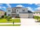 Charming two-story home with a three-car garage and stone accents, set against a backdrop of lush landscaping and a bright blue sky at 16410 Good Hearth Blvd, Clermont, FL 34711