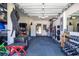 Organized garage featuring gym equipment, storage shelves, and rubber flooring for workouts at 16410 Good Hearth Blvd, Clermont, FL 34711
