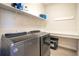 Convenient laundry room with modern washer and dryer units, shelving, and a folding counter at 16410 Good Hearth Blvd, Clermont, FL 34711