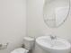 Powder room with pedestal sink, oval mirror, and toilet at 17081 Water Spring Blvd, Winter Garden, FL 34787