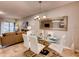 Elegant dining area featuring a glass table, white chairs, decorative mirror, and views into the living room at 17081 Water Spring Blvd, Winter Garden, FL 34787
