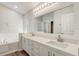 Bright bathroom features double sinks, quartz counters, bathtub, and large mirror at 19540 Glen Elm Way, Orlando, FL 32833