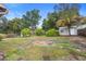 Landscaped backyard with lawn, shrubbery, shade trees, and a shed in the distance under a sunny sky at 2123 Weber St, Orlando, FL 32803