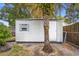 Exterior view of the backyard shed with siding, door, and window, surrounded by vegetation and a palm tree at 2123 Weber St, Orlando, FL 32803