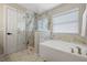 Bright bathroom with a soaking tub, glass enclosed shower, marble tile, and modern fixtures at 2447 Hassonite St, Kissimmee, FL 34744