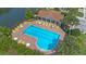 Community pool with inviting blue water, surrounded by lounge chairs, umbrellas, and lush landscaping at 2447 Hassonite St, Kissimmee, FL 34744