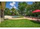 Lush backyard with pool, red umbrellas, well-manicured lawn, brick pathway, and outdoor seating area, great for relaxing at 2491 Island Dr, Longwood, FL 32779