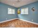 Empty bedroom showcasing blue walls, parquet floors, and windows with blinds at 2491 Island Dr, Longwood, FL 32779
