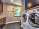 Well-equipped laundry room with dark cabinets, stainless steel washer and dryer, and a window at 2491 Island Dr, Longwood, FL 32779